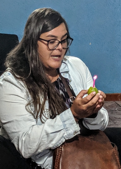 Person holding a lit candle placed on a lime.