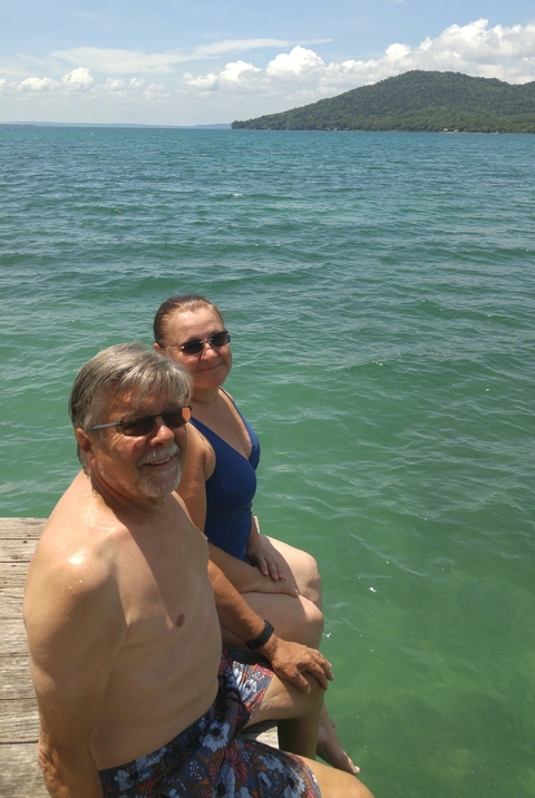 Two people wearing sunglasses near a body of water.