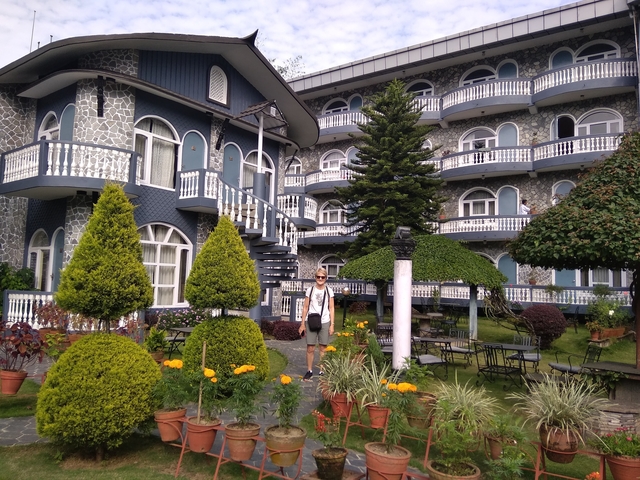 Tourist standing in front of a hotel with landscaped gardens.