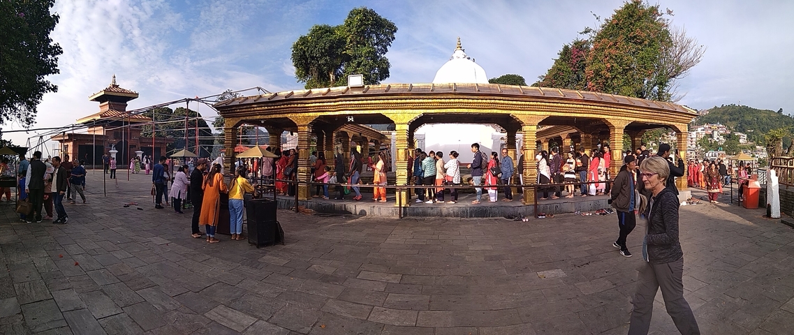       People gathered around a golden-roofed structure in a temple.
  