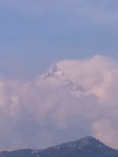 Distant snow-covered mountain peak partially shrouded in clouds.