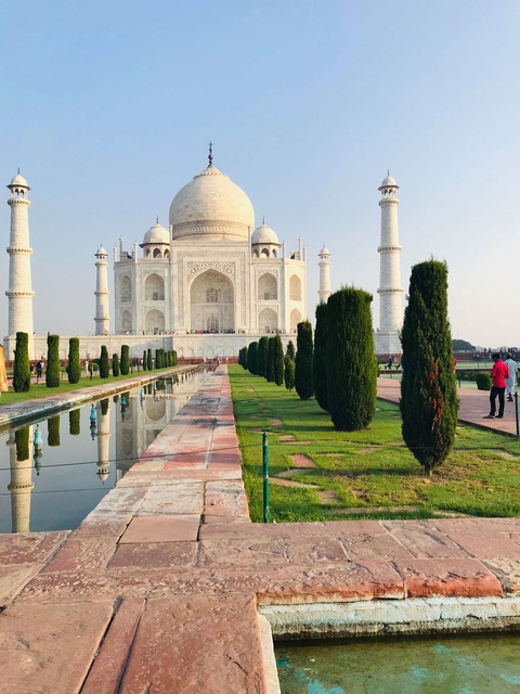       View of the Taj Mahal with reflecting pool and visitors.
  