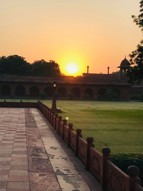      Sunset over historical architecture with well-manicured lawn.
  