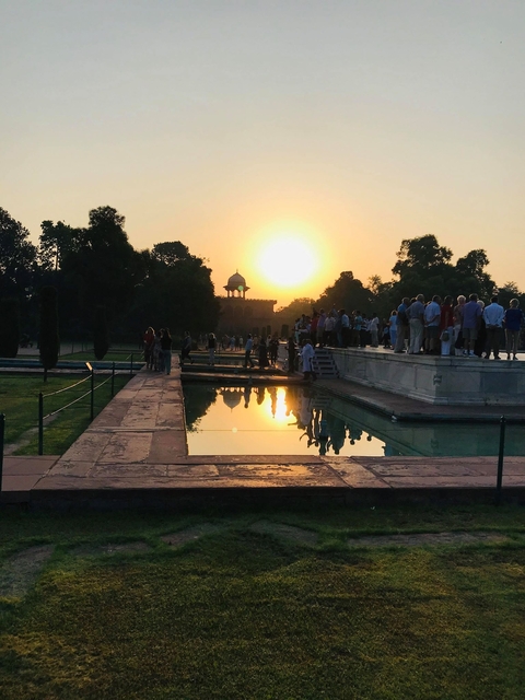       Crowd enjoying sunset over a reflective water surface at the Taj Mahal.
  