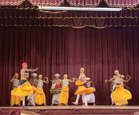       A traditional dance performance with dancers in colorful costumes on stage.
  