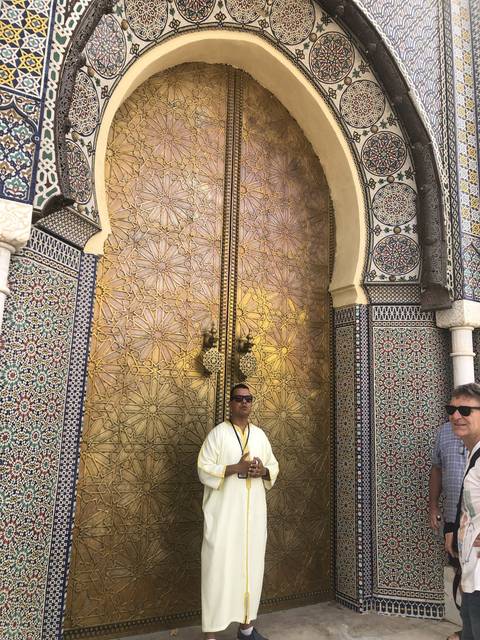       A person in traditional attire in front of an ornately decorated door.
  