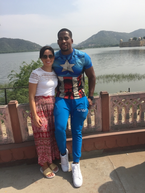 A couple posing for a photo with a body of water in the background.