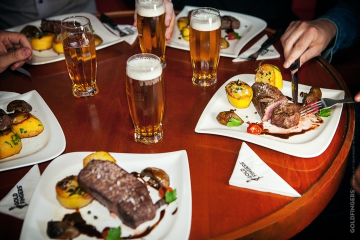 Plates of food with drinks on a table in a social setting.