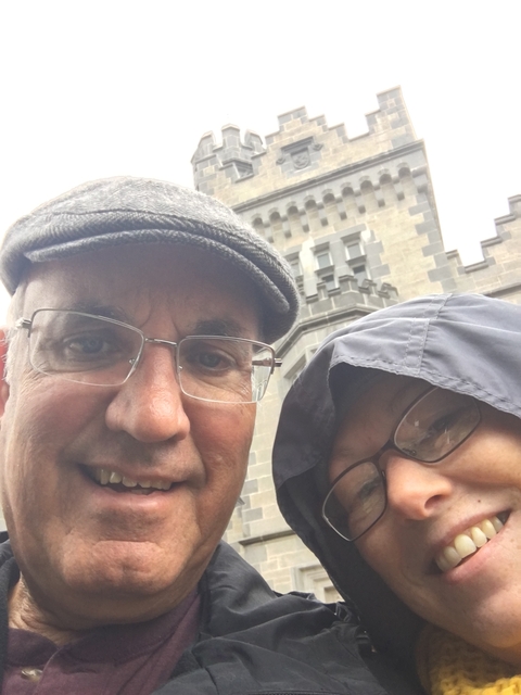Close-up of two people with a stone building in the background.