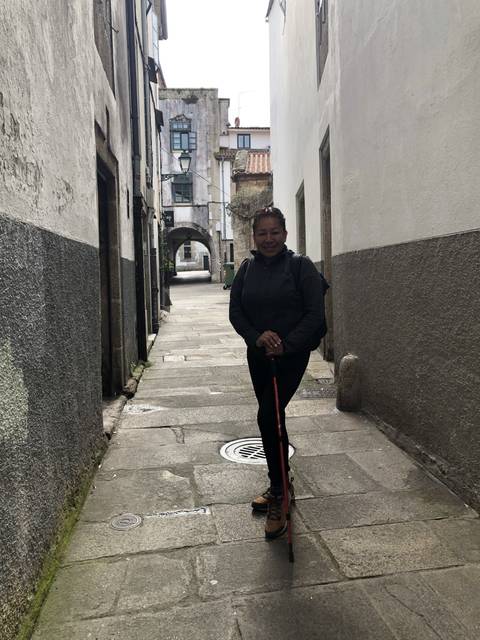 A person standing in a narrow alley with walking sticks.