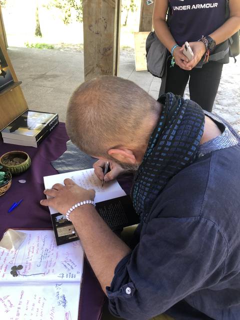 Person writing in a book at an outdoor table.