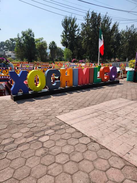 Colorful sign spelling 'Xochimilco' with surrounding trees.