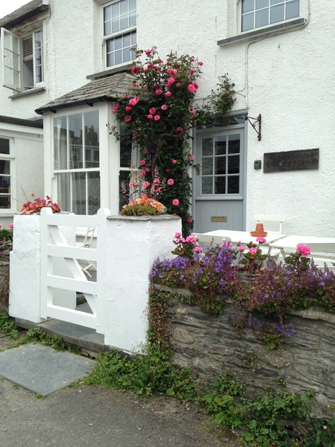 Charming cottage with flowers and a small table outside.