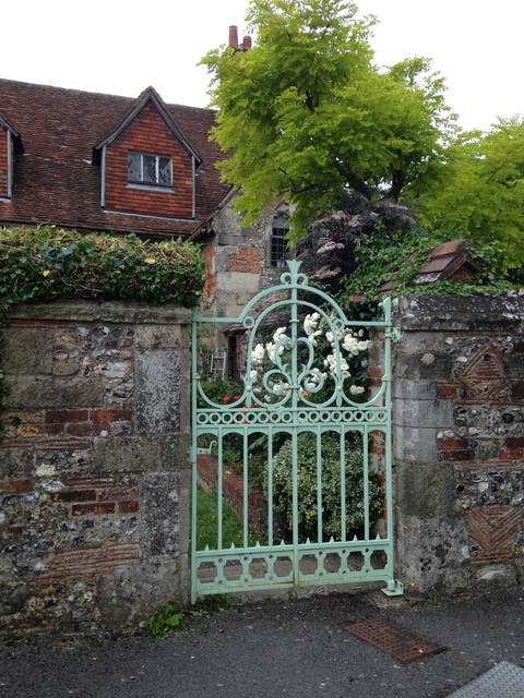       Ornate gate with flowers in a garden setting.
  