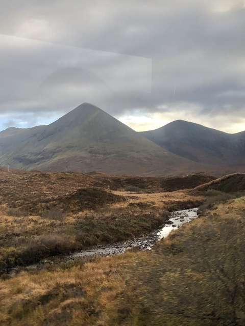       Mountain range with clear sky, a stream runs through the foreground.
  