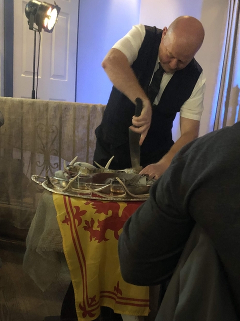       Person carving a meal in front of Scottish flag.
  