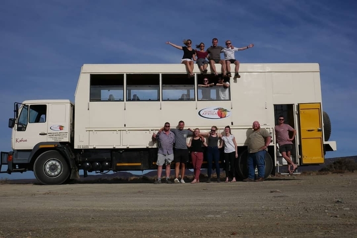 Group of people next to a large tour vehicle.