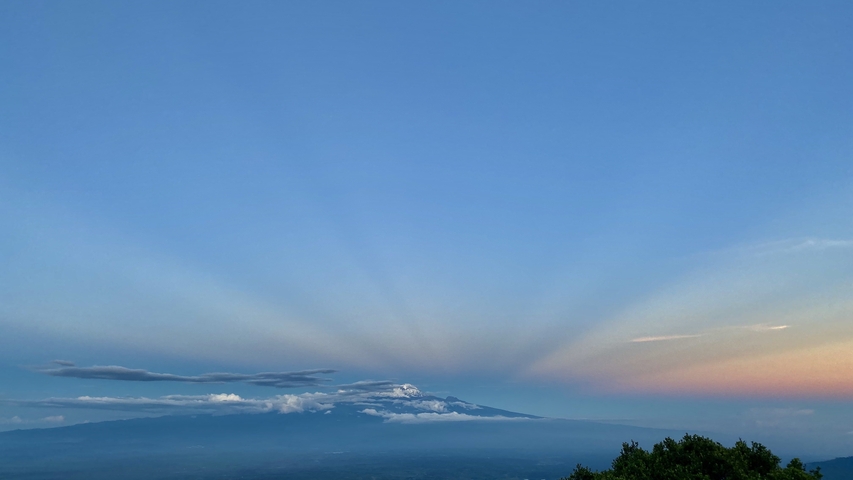       Expansive view of a mountain silhouette under striking sky colors.
  