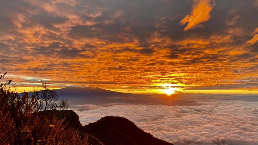       Spectacular sunrise with clouds and a silhouetted mountain.
  
