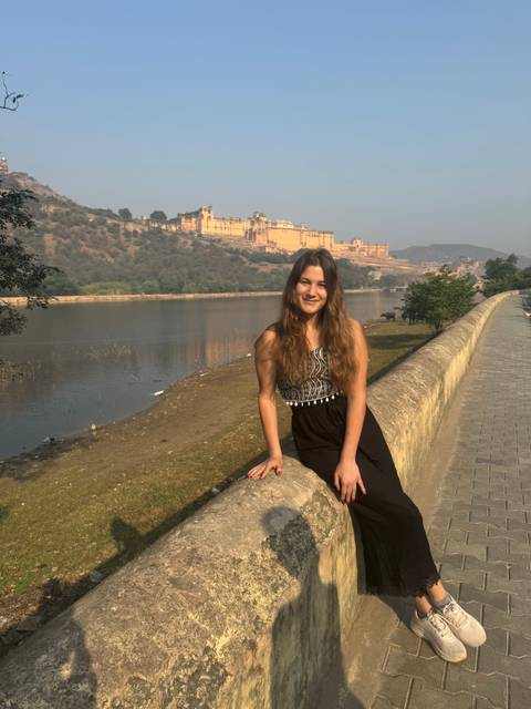 Person sitting on a wall with Amber Fort in the background.