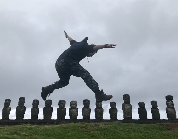 Man balancing creatively on Moai statues.