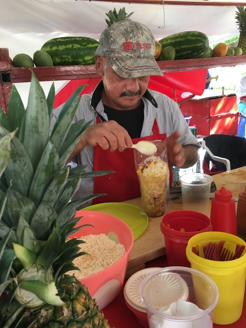       Man preparing a fruit dessert at a street market.
  