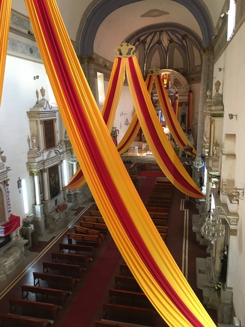       Inside of a church adorned with vibrant drapery.
  