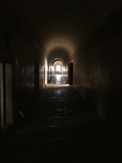       A dimly lit hallway with an arched entrance.
  