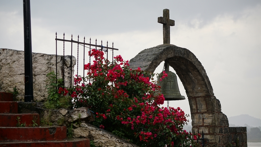       Bell arch with vibrant flowers against an overcast sky.
  