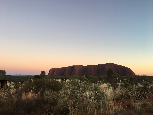Uluru under a pastel-colored sky at dusk.
