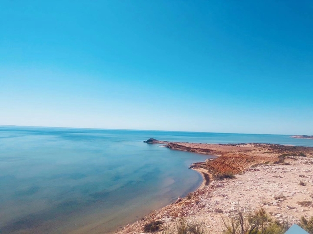 A coastline with calm blue waters and a lightly clouded sky.