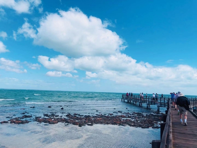 People walking on a pier extending into the ocean.