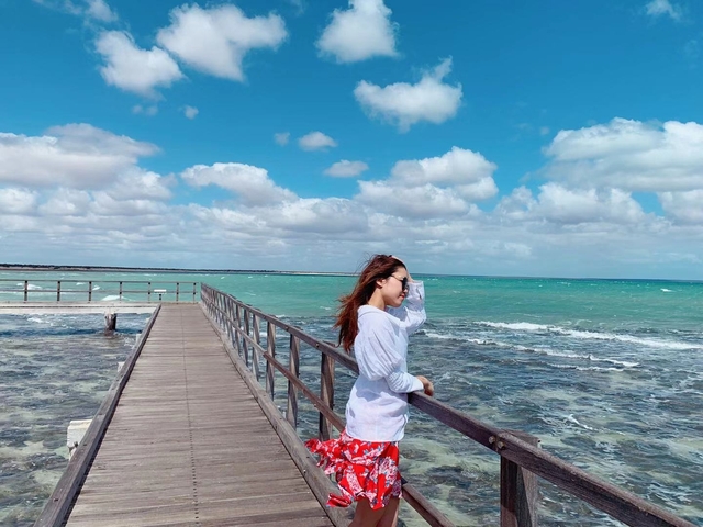 A woman standing on a boardwalk beside a large ocean.