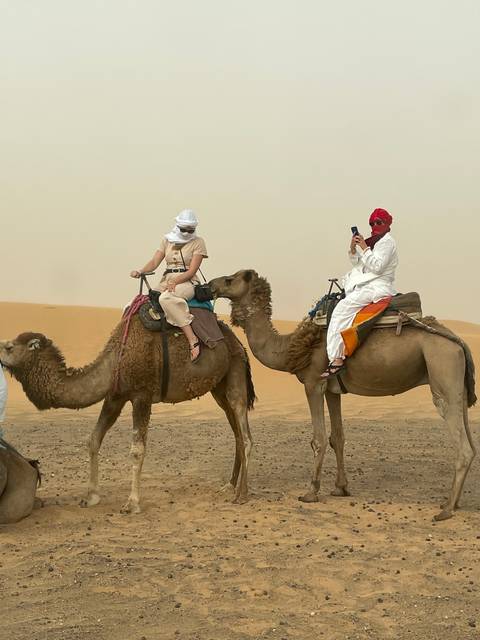 People riding camels in a desert setting.