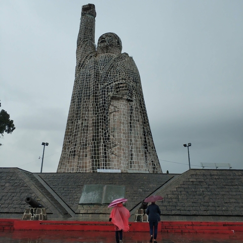       Large statue wrapped in a metallic grid structure.
  