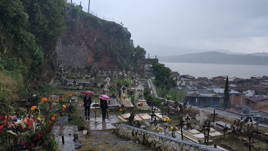      Cemetery overlooking a lake with people holding umbrellas
  