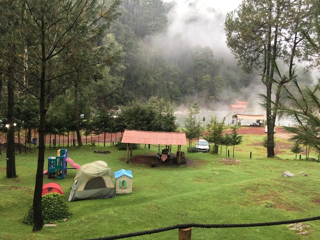       Camping area with tents and fog over a forest
  