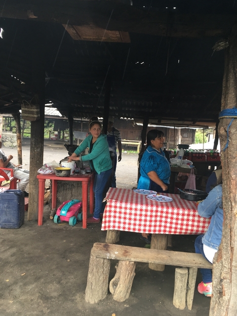       Women preparing food at a market stall.
  