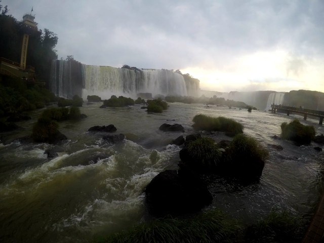       Wide view of Iguazu Falls with water rushing over rocks.
  