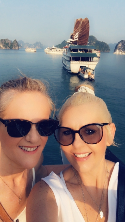 Two women wearing sunglasses on a boat with water in the background.