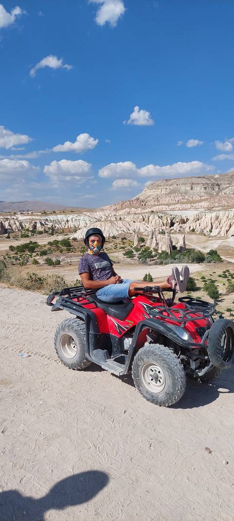 Person lying on an ATV with rocky landscape in the background.