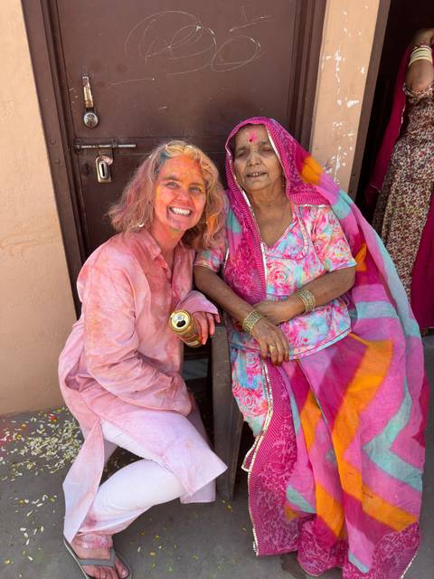       Women sitting together in traditional attire during Holi.
  