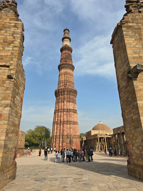       Tall historical tower surrounded by tourists.
  