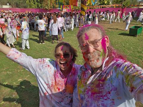      People covered in Holi colors in a festive setting.
  