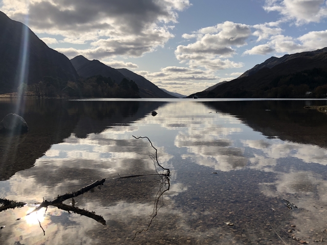       Silky waters of a tranquil lake reflecting clouds and mountains.
  