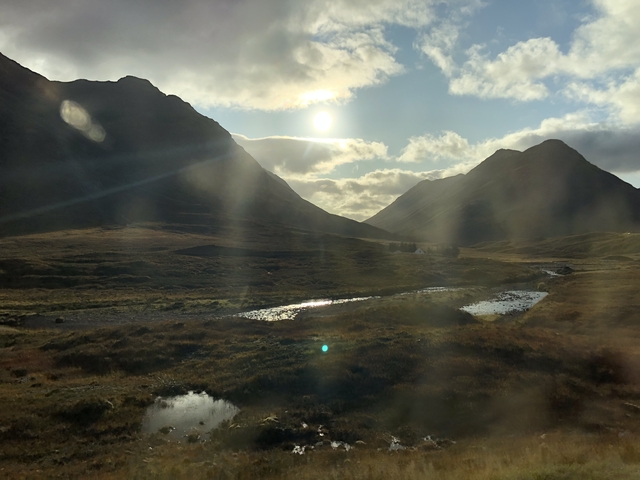       Sunlight filtering through clouds over a mountain valley.
  