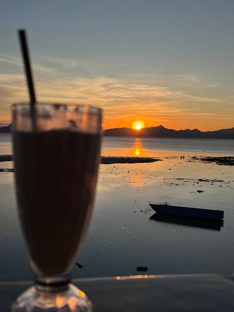 Sunset over water with a glass in the foreground.