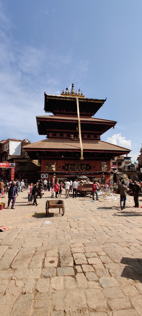       Busy market scene in front of a traditional Nepalese building.
  