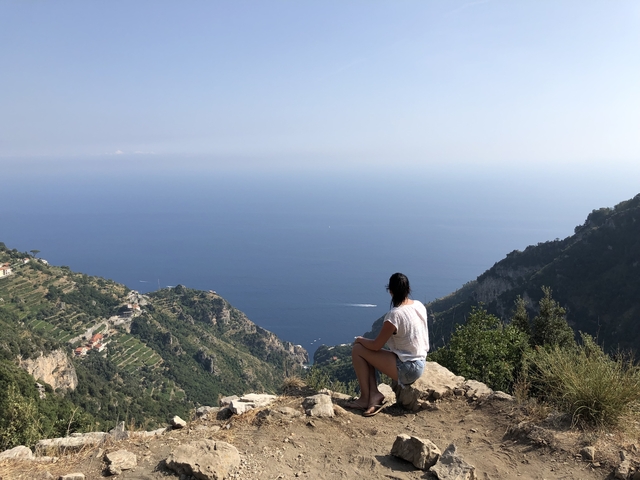 Person seated looking over vast sea landscape.