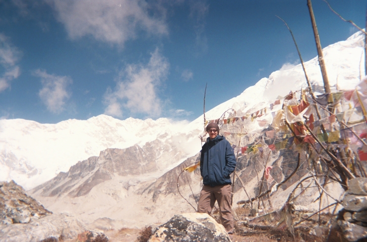 Person standing with colorful prayer flags in the mountains.